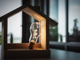ampoule dans une petite maison en bois représentant les économies d'énergies