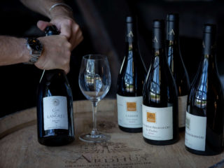 plusieur bouteilles de vin du domaine vinicole d'Ardhuy sur un tonneau