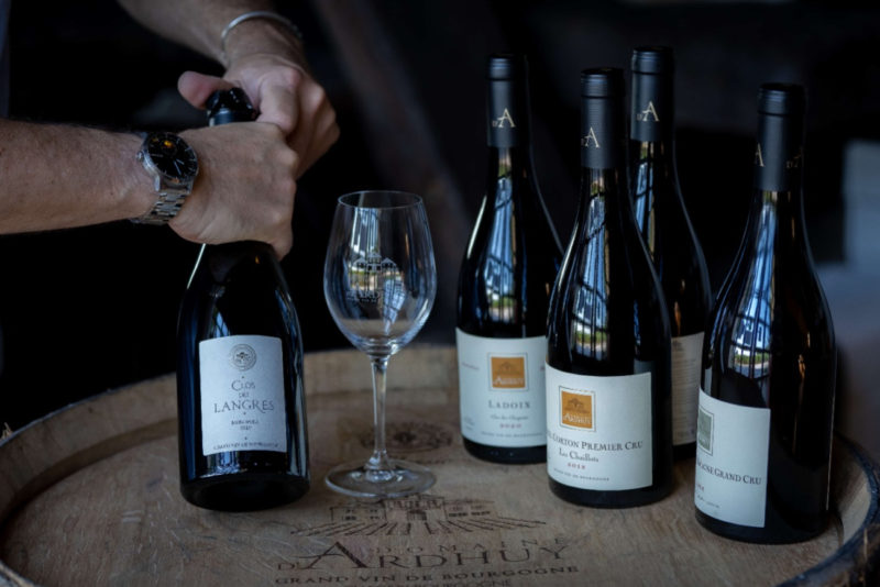 plusieur bouteilles de vin du domaine vinicole d'Ardhuy sur un tonneau