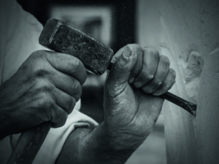 photo en noir et blanc d'une personne taillant de la pierre
